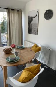 a dining room table with chairs and a clock on the wall at Modernes Apartment in Haiger Allendorf in Haiger