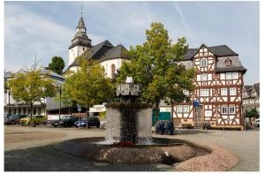 a fountain in front of a building with a clock tower at Modernes Apartment in Haiger Allendorf in Haiger