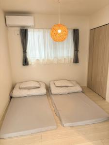 a room with three mattresses in front of a window at 新築一棟貸切 民宿 夢 駐車場2台無料 コンビニ徒歩2分 市街地へ好アクセス in Matsuyama