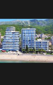 two tall buildings on a beach next to the ocean at La Fiaba Rafailovici Apartment in Rafailovici