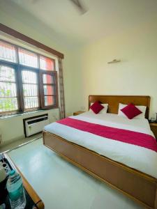 a bedroom with a large bed with red pillows at Hotel Har Ki Pauri with terrace Ganga view in Haridwār
