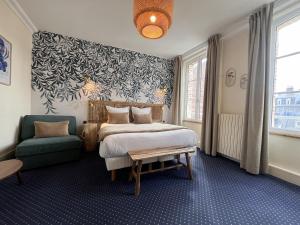 a bedroom with a bed and a chair in it at Le Trouville - Hôtel de Charme in Trouville-sur-Mer