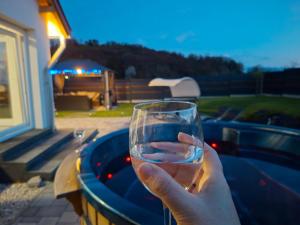 a person holding up a glass of water at Napsugár Wellness Apartman in Újudvar +29 photos