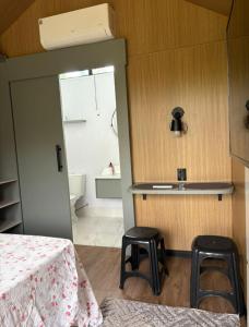 a room with a bed and two stools and a bathroom at Chalé Loft in Lavrinhas +6 photos