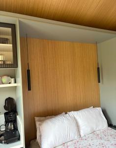 a bed with a wooden headboard in a room at Chalé Loft in Lavrinhas