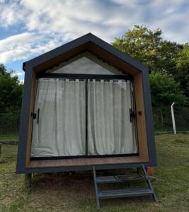 a small house with a white curtain in the grass at Chalé Loft in Lavrinhas