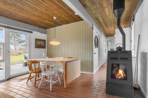 a kitchen with a table and a stove and a fireplace at 84307-8400-Skovduevej-4 in Fuglslev