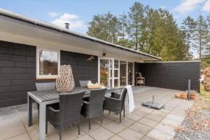 a patio with a table and chairs and a house at 84307-8400-Skovduevej-4 in Fuglslev