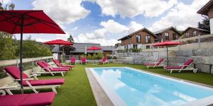 a pool with chairs and red umbrellas next to a building at Chaletpark Diemelsee in Heringhausen