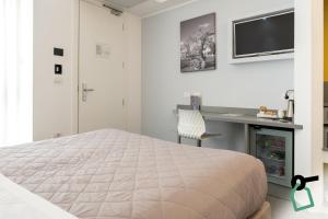 a white bedroom with a bed and a desk at Hotiday Brindisi Vittoria in Brindisi