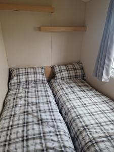 two beds sitting next to each other in a room at Buttercup Retreat 298 northfield in Skipsea +13 photos
