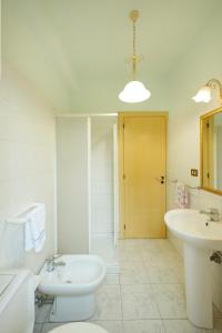 a white bathroom with a sink and a toilet and a tub at Armonia del Mare in Mascali +5 photos