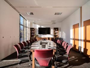 a conference room with a long table and red chairs at Flemings Hotel Bremen-Hauptbahnhof in Bremen