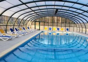 a large swimming pool with chairs in a building at Chalet in Marcilly-sur-Eure