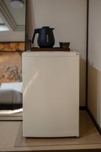 a tea kettle on top of a white refrigerator at oyasumi hotel 道頓堀 Zero-pressure mattress in Osaka