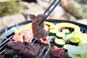 a piece of meat on a grill with vegetables at Banksia Seaside Cottage in Ōami