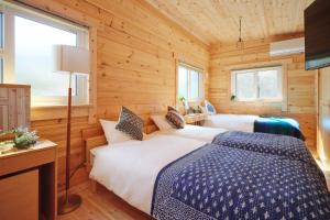 a bedroom with two beds in a wooden cabin at Banksia Seaside Cottage in Ōami