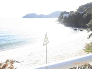een bord op een strand naast het water bij Oyajino Umi in Naoshima
