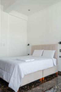 a white bed with white sheets and pillows at Mansion Altamirano Hotel in San Antonio