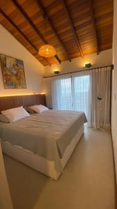 a bedroom with a large bed and a chandelier at Pousada Casa Zoe Búzios in Búzios