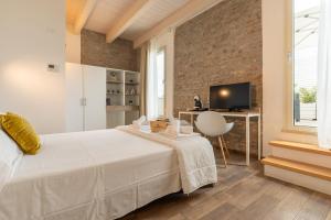 a bedroom with a white bed and a brick wall at Club del Sole Vigna sul Mar Family Collection in Lido di Pomposa