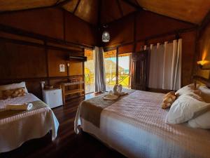 a bedroom with two beds and a large window at Vila Riomar in Luis Correia