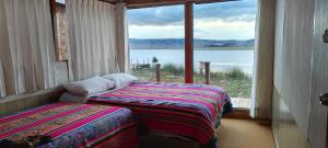 two beds in a room with a view of the water at Los Uros in Puno