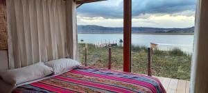 a bedroom with a large window looking out at a lake at Los Uros in Puno