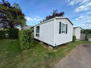 a white tiny house sitting in a yard at Camping Paradis l'Arada Parc in Sonzay