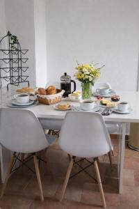 a dining room table with two white chairs and a table with food at Wildblick Appartment Hof Grindelborn in Mürlenbach