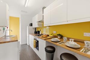 a kitchen with white cabinets and a yellow wall at 4BR with Private Parking in Wyken