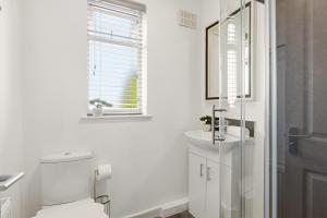 a white bathroom with a toilet and a sink at 4BR with Private Parking in Wyken +22 photos