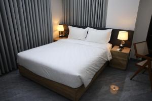 a bedroom with a bed with white sheets and pillows at Pearl Serenity in Sholāshahar