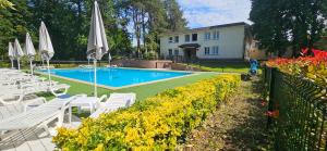 a pool with white chairs and umbrellas in a yard at Le Manoir Hôtel Le Touquet Paris Plage in Le Touquet-Paris-Plage