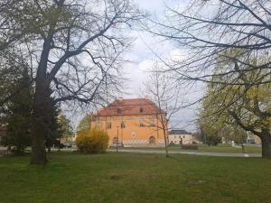 a large orange building in a park with trees at Apartmán u parku in Prostějov