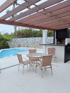 a patio with a table and chairs next to a pool at Pousada Casa Zoe Búzios in Búzios
