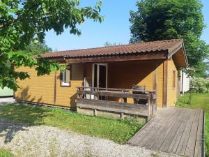 a small wooden cabin with a wooden walkway in front at Camping Onlycamp Les Peupliers du Lac in Chindrieux