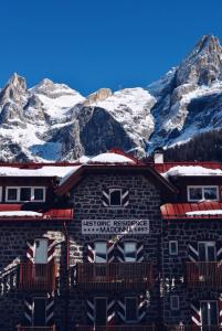 um edifício com montanhas cobertas de neve ao fundo em Historic Residence Madonna em San Martino di Castrozza