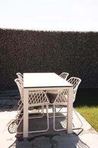 a white table with four wicker chairs around it at Huisje Meersen in Maldegem