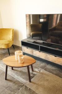 a living room with a table and a large tv at Huisje Meersen in Maldegem