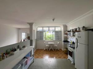 a kitchen with a white refrigerator and a table at Quarto com varanda privada a 160 metros da Praia do Farol da barra 3 in Salvador