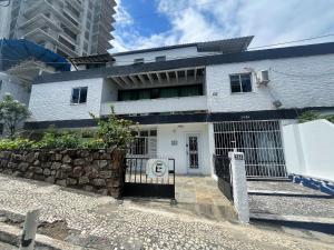 a white house with a gate in front of it at Quarto com varanda privada a 160 metros da Praia do Farol da barra 3 in Salvador
