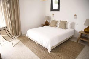 a bedroom with a white bed and a chair at Stylish Villa, Rural Setting, Infinity Pool in Pano Akourdalia +35 photos
