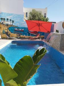 ein Schwimmbad mit einem roten Sonnenschirm und einem Gemälde in der Unterkunft Djerba Aldo Piscine in Houmt Souk