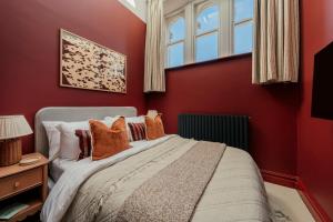 a bedroom with a bed with red walls and a window at St James Apartments - Harrogate in Harrogate +90 photos