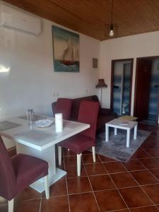 a living room with a white table and red chairs at Kuca za odmor Maestral in Privlaka