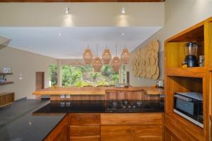 a large kitchen with wooden cabinets and a window at Villa Canopy - Spacious Luxury 4BR Villa Near Nuanu and Luna Beach Club in Tabanan