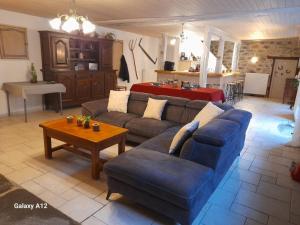 a living room with a blue couch and a table at LA LONGÈRE - Chambres et table d'hôtes in Alpuech