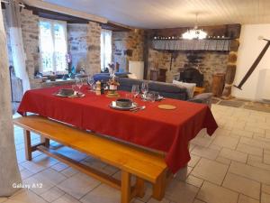 a table in a living room with a red table cloth at LA LONGÈRE - Chambres et table d'hôtes in Alpuech