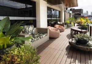 a patio with a couch and tables and plants at Hotel Palmas Executivo in Balneário Camboriú